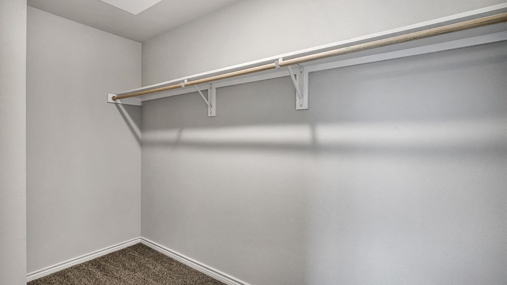 our spacious closets in our apartments have a large closet with a white wall and