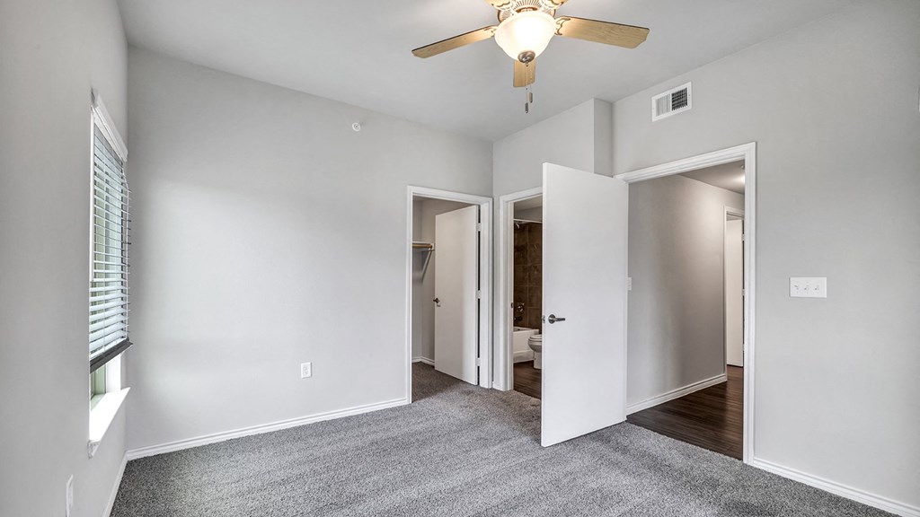 a bedroom with a ceiling fan and a door to a bathroom