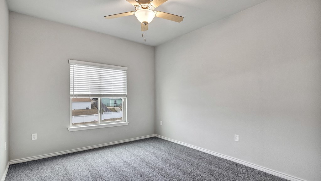 an empty bedroom with a ceiling fan and a window