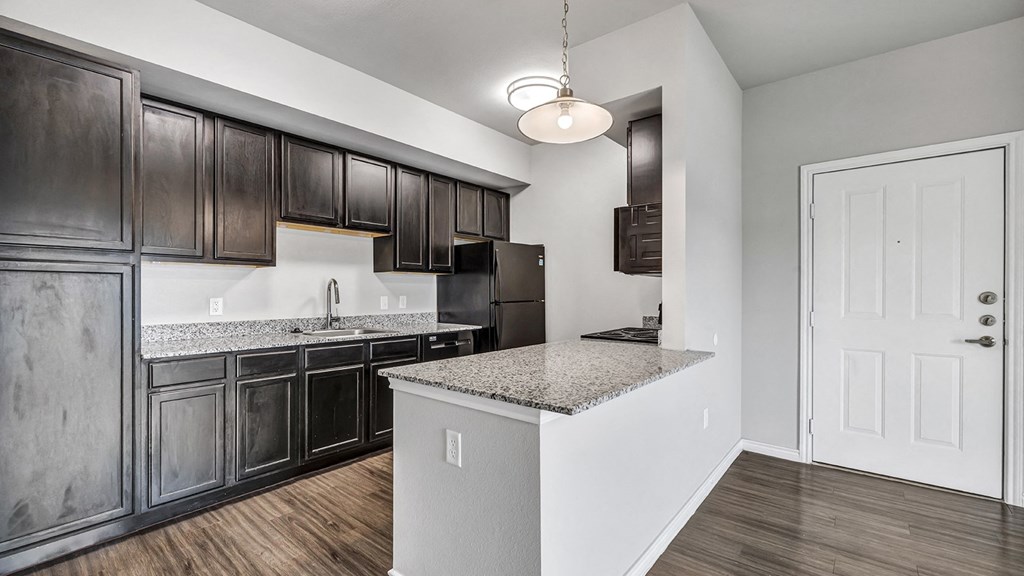 an empty kitchen with dark cabinets and granite counter tops