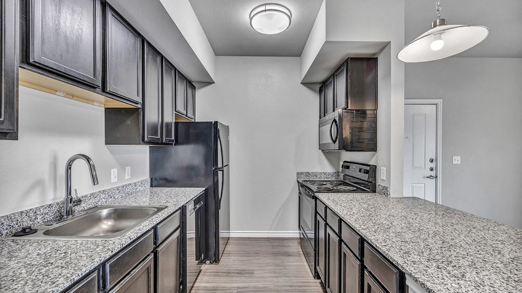 an empty kitchen with granite counter tops and a stainless steel refrigerator