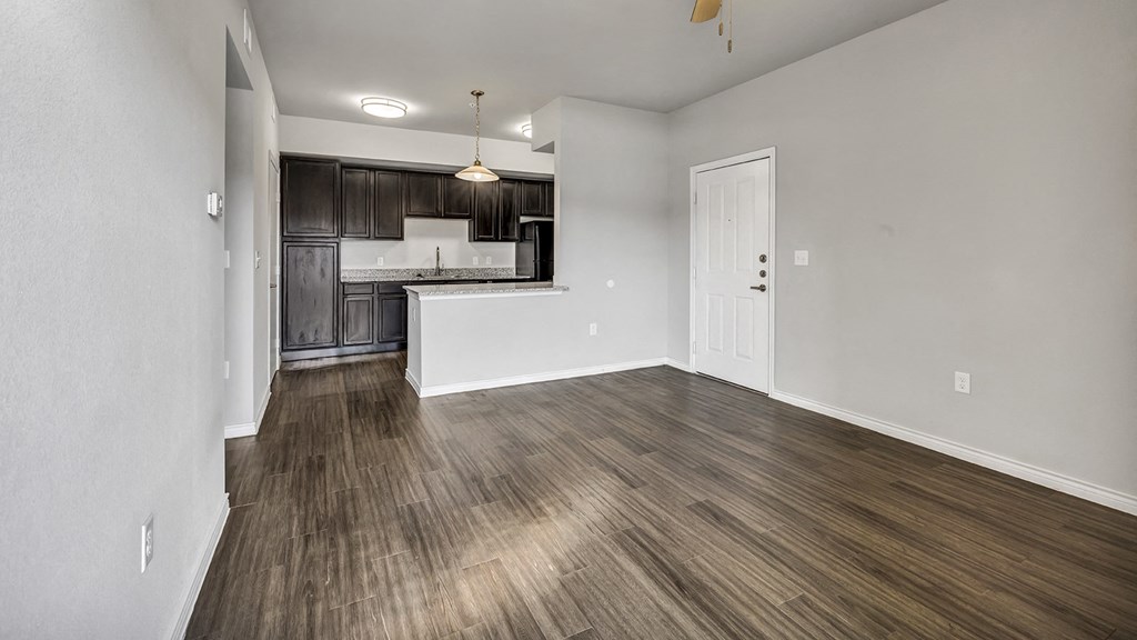 the living room and kitchen of an empty apartment with wood flooring
