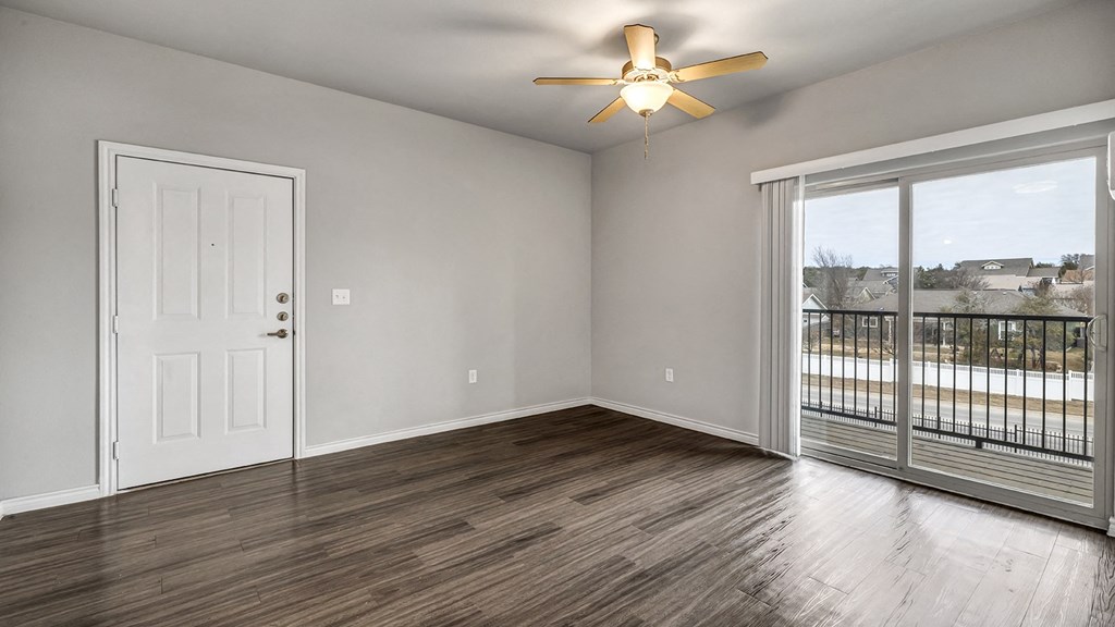 an empty living room with a balcony and a ceiling fan