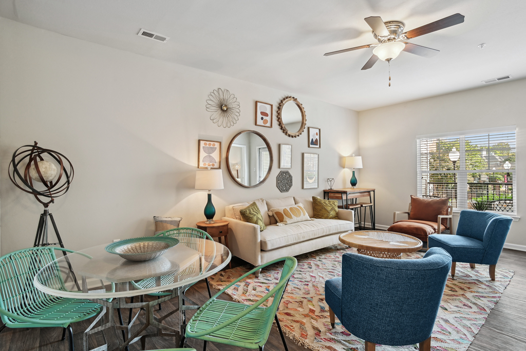 a living room with a ceiling fan and a round glass table