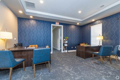 A room with blue chairs and a wooden desk.