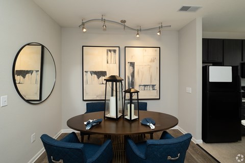 A dining room with a round table and blue chairs.