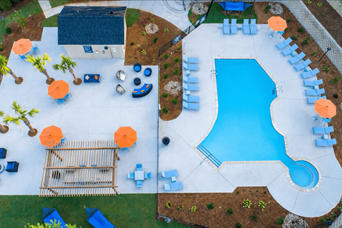 A pool with a slide and a deck with sun loungers.