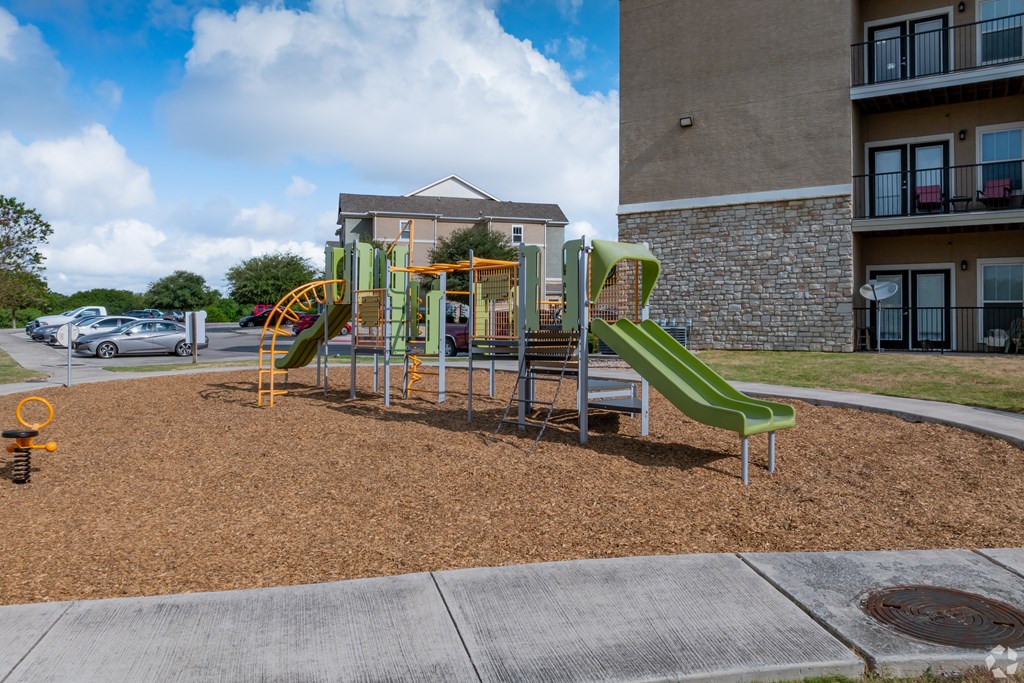 A playground with a green slide and a yellow slide.