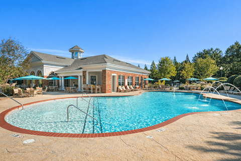 A large swimming pool in front of a building with a gazebo.