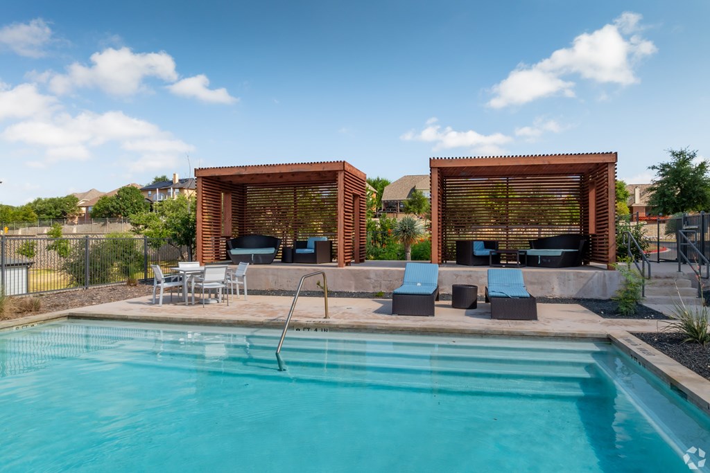 A swimming pool with a diving board and two sun shades.