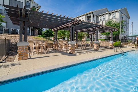 A swimming pool with a wooden pergola over it.