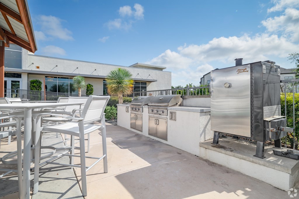 A patio with a table and chairs and a BBQ grill.