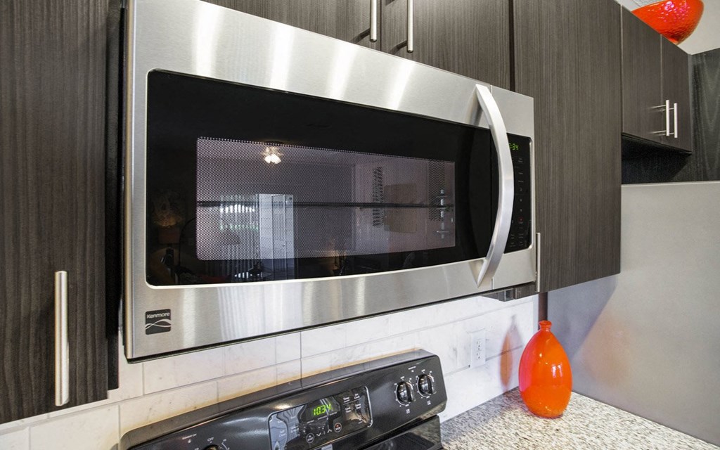 A modern kitchen with a stainless steel microwave and oven.