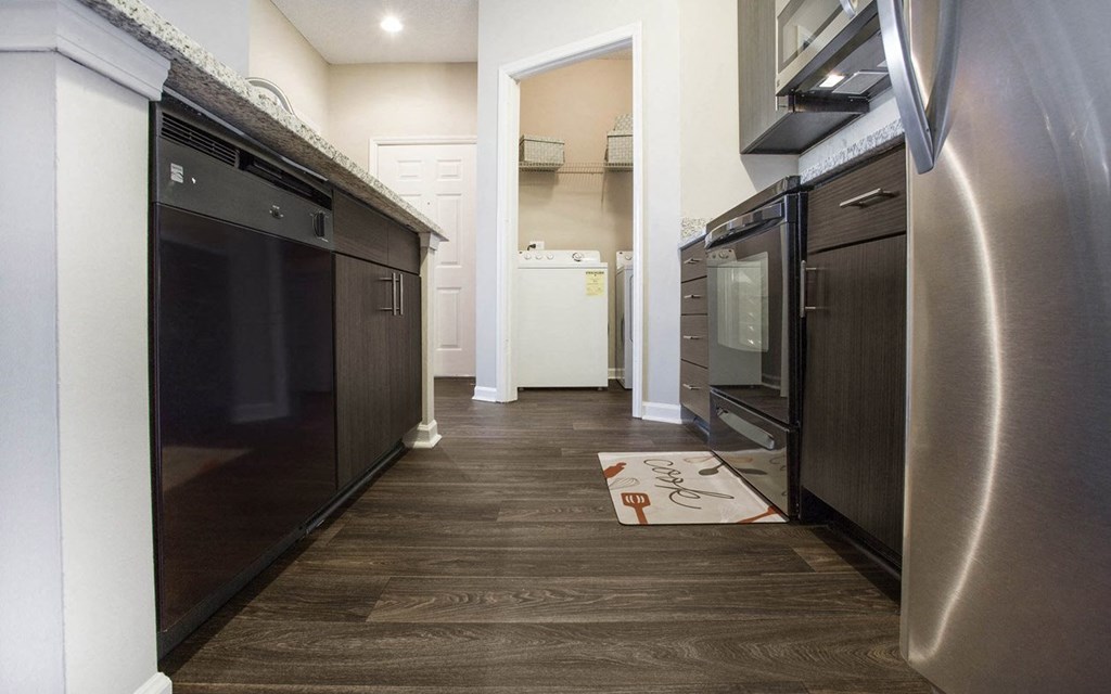 A modern kitchen with dark wood floors and stainless steel appliances.