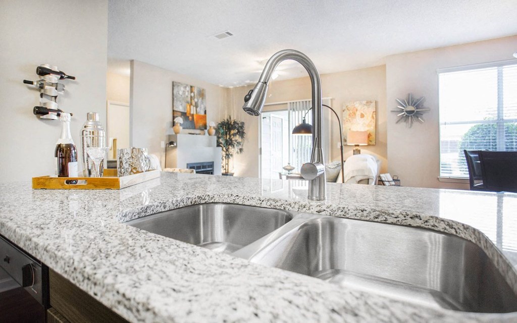 A kitchen with a marble countertop and a stainless steel sink.
