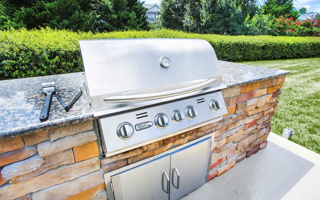 A stainless steel grill is built into a brick wall.