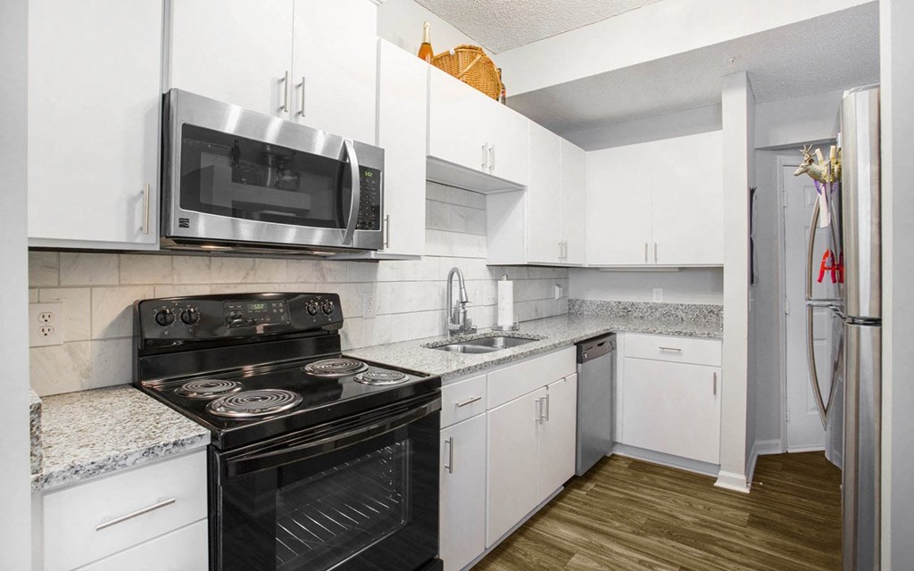 A kitchen with white cabinets and a black stove top oven.