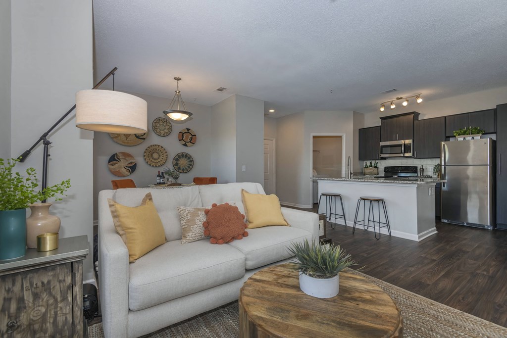 a living room at Seasons at Umstead apartments in Raleigh with a white couch and a wooden coffee table in front of a kitchen
