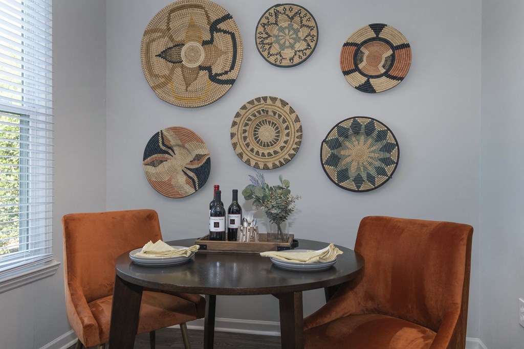 a dining area Seasons at Umstead apartments in Raleigh with a table and two orange chairs