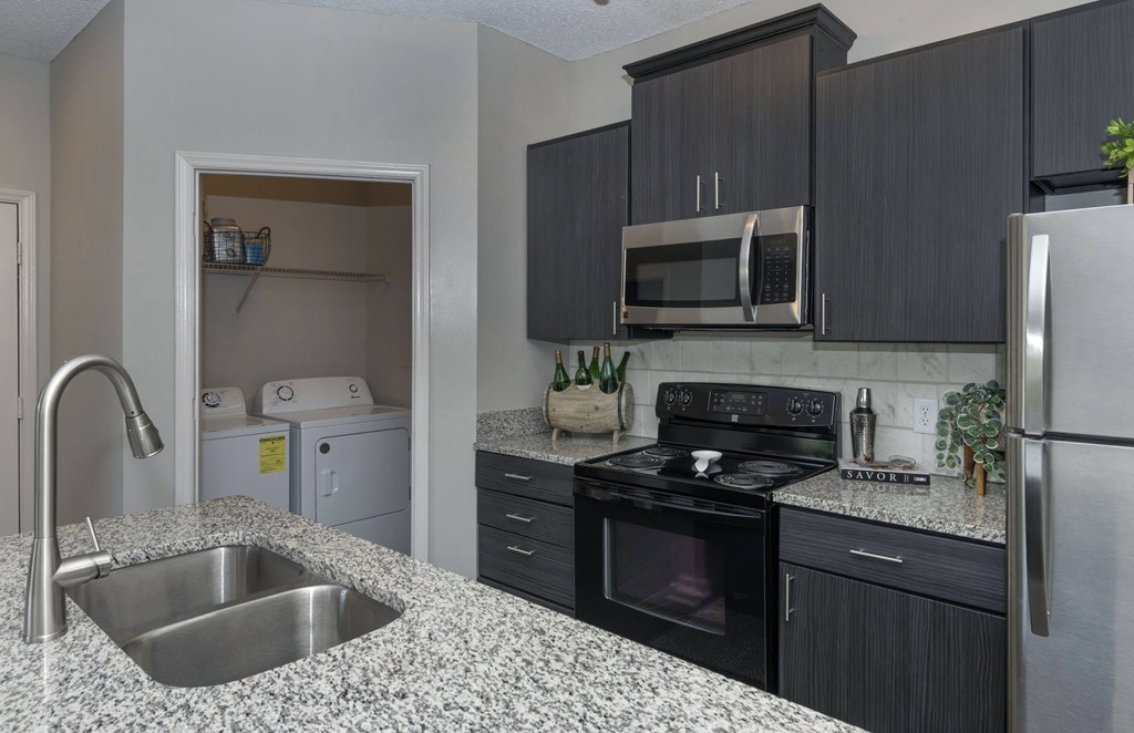 Seasons at Umstead apartments in Raleigh interior kitchen renovated appliances with view into washer dryer closet