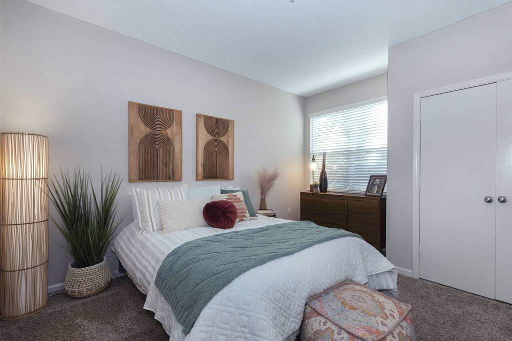 a bedroom with a bed and a dresser in front of a window