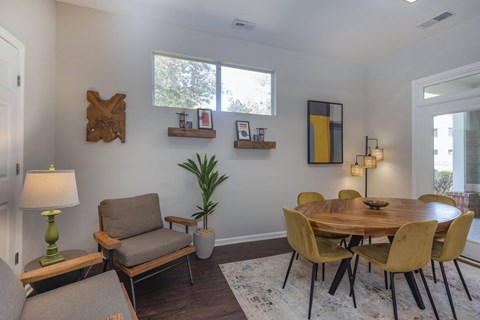 a dining area with a round wooden table and yellow chairs at Seasons at Umstead apartments in Raleigh