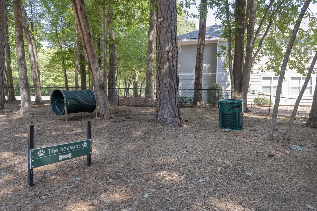 Bark park surrounded by trees with dog exercise equipment at  Seasons at Umstead apartments in Raleigh