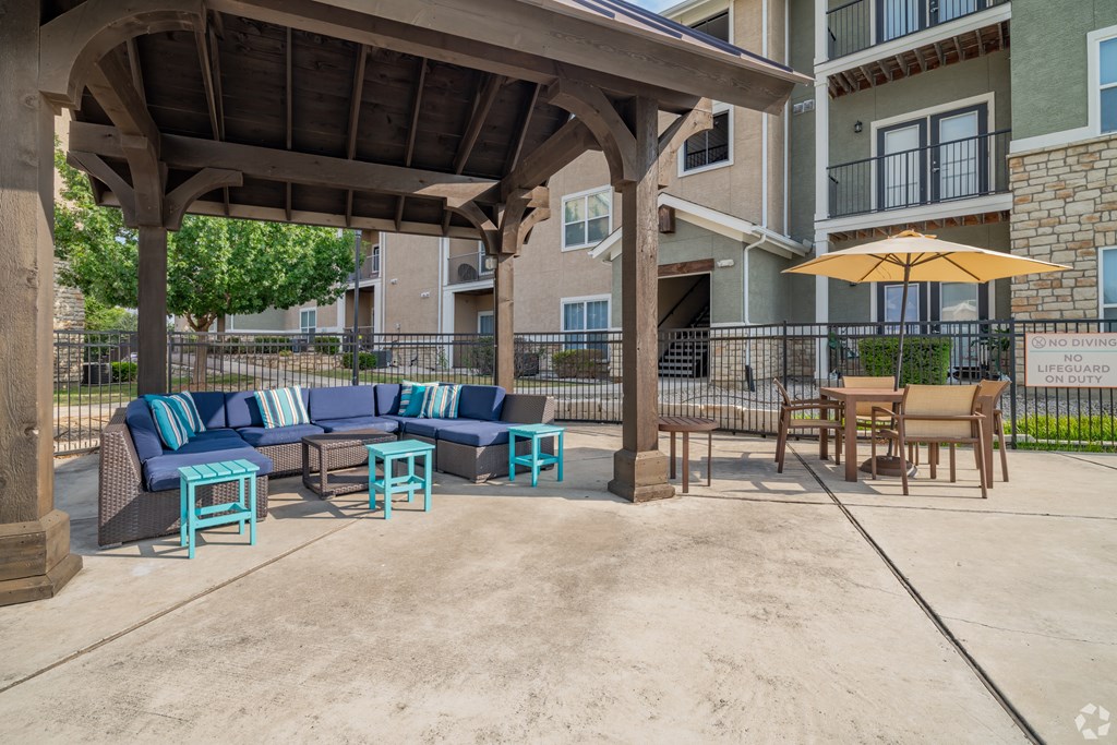 A patio with a couch, chairs, and an umbrella.