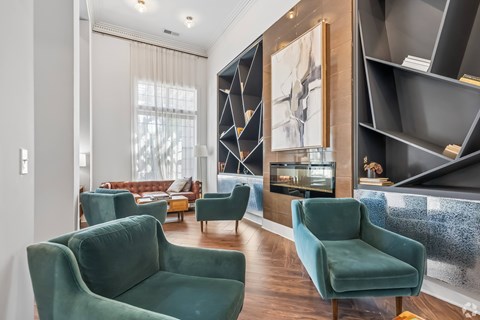 A living room with green chairs and a large painting on the wall.