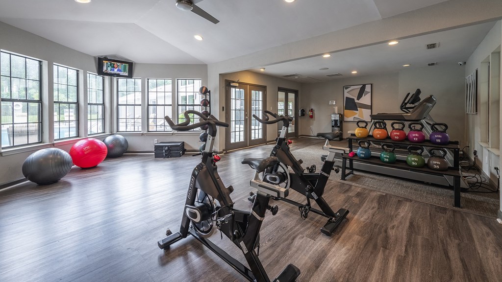 a modern apartment complex gym with weights and cardio equipment and windows