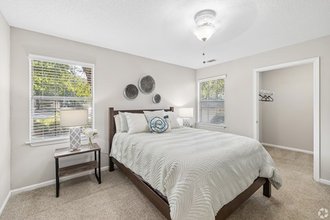 A bedroom with a bed, nightstand, and window.