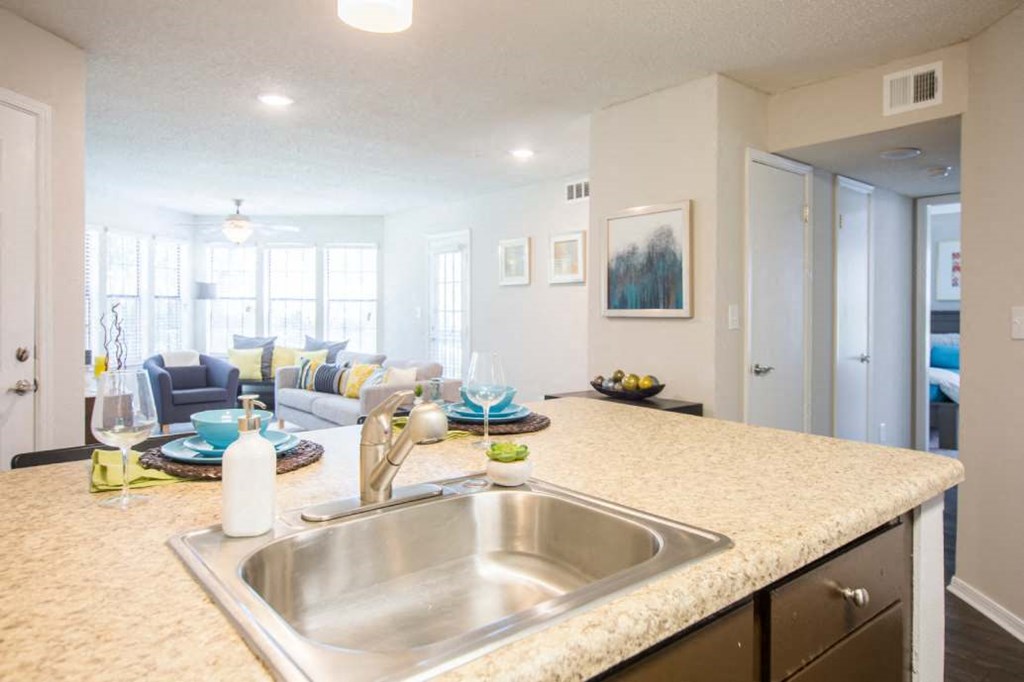 a kitchen counter top with a sink and a living room