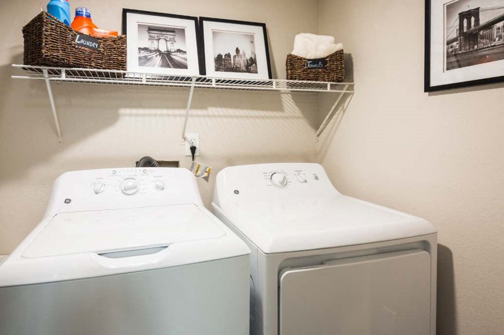 a washer and dryer in a laundry room with pictures on the wall