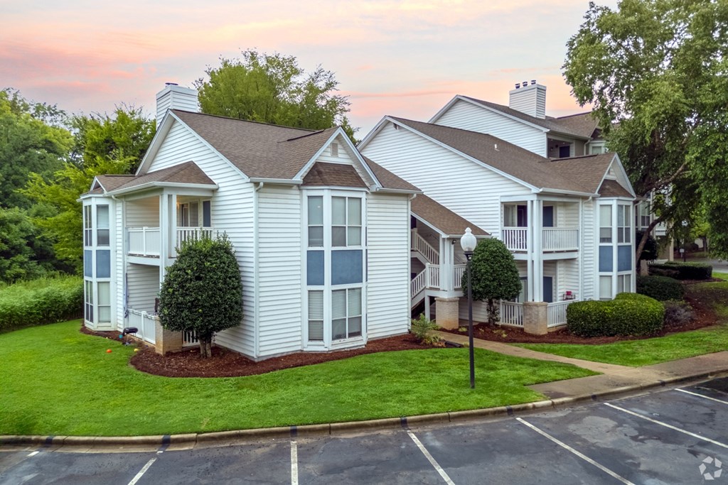 A white house with a brown roof and a green lawn.