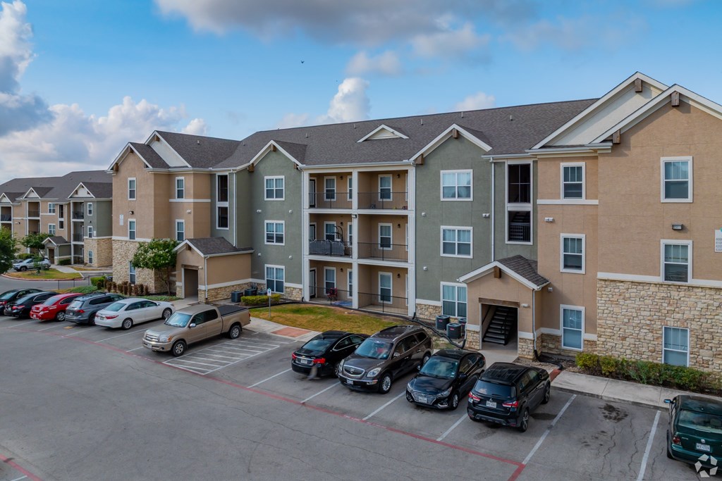 A parking lot in front of a multi-story apartment building.