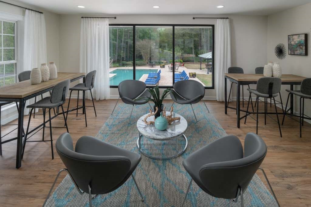 Veridian at Sandy Springs apartments leasing center resident clubhouse interior with tables and chairs and a pool in the background