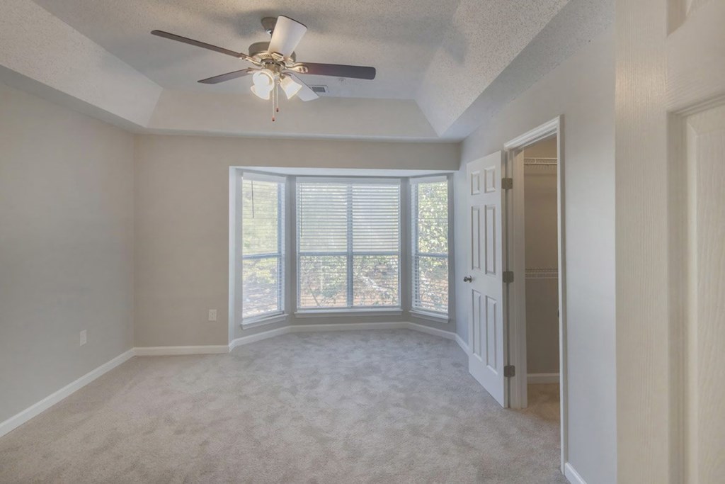 A room with a ceiling fan and sliding glass doors.