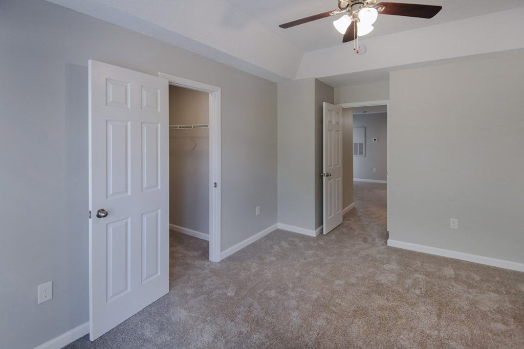 A room with a ceiling fan and carpeted floor.