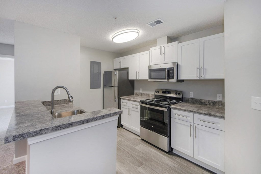 A kitchen with white cabinets and a granite countertop.