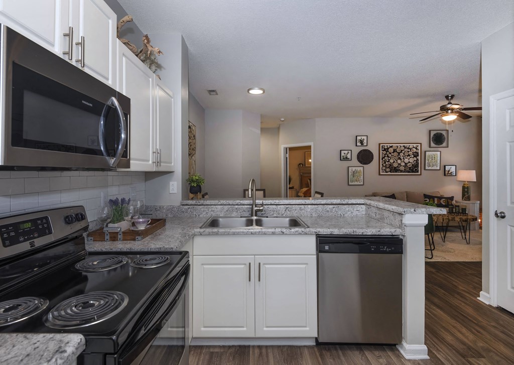a kitchen with white cabinets and black appliances at Whitehall Estate apartments in Charlotte NC