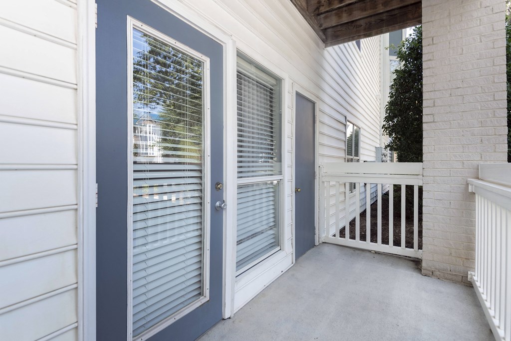 a private patio with a glass door and a porch with a railing at Whitehall Estate apartments in Charlotte NC