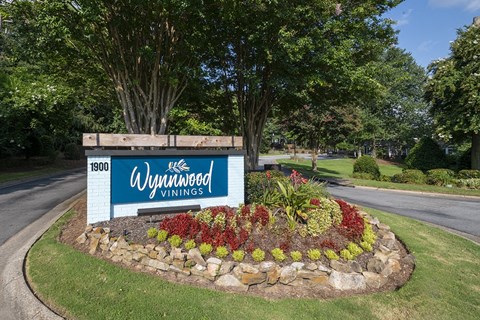 a sign for Wynnwood Vinings apartments on a roundabout with a flower garden