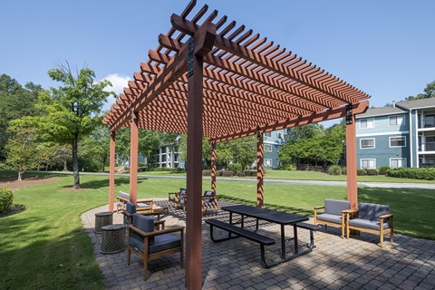 a patio with a picnic table and chairs under a pergola at Wynnwood Vinings apartments