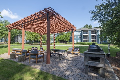 a group of tables and chairs in an outdoor picnic BBQ area at Wynnwood Vinings apartments