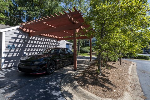 a car parked in a Car Wash amenity at Wynnwood Vinings apartments under a wooden shade