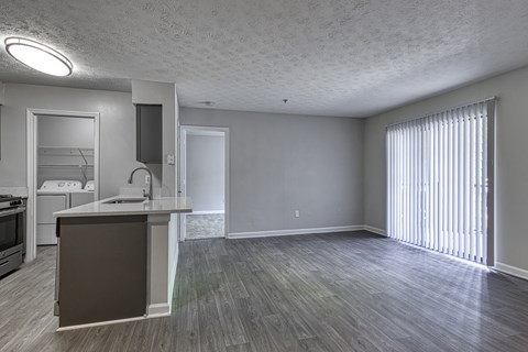an empty living room and kitchen with a large window
