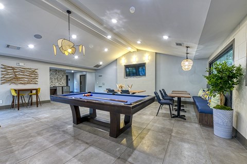 A room with a pool table and a tv mounted on the wall.