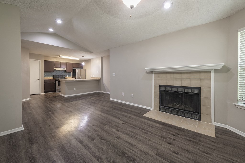 Duluth, GA Apartments with In-Unit Washer and Dryer - The Eclipse - Unfurnished Living Room with Designer Wood Look Plank Flooring, a Fireplace, Ceiling Fan, Window, Near an Open-Concept Kitchen Layout