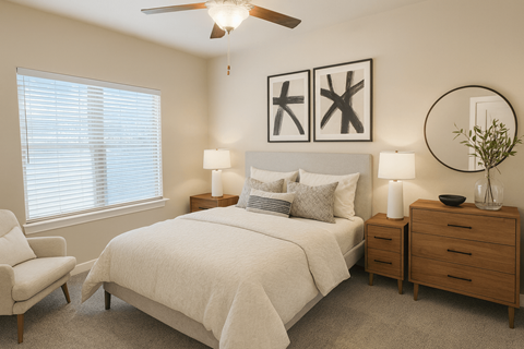 Stone Oak, TX, Apartments with In-Unit Washer and Dryer - Encore 281 Apartment Homes - Bedroom With Large Window, Ceiling Fan, Neutral Bedding, Framed Wall Art, And Wood Dresser With Round Mirror.