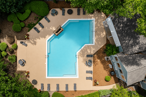 3-Bedroom Garden-Style Apartments in Tucker, GA - Capella Apartment Homes - Aerial View of Resort-Style Swimming Pool With Sundeck, Lounge Chairs, Patio Tables, and Green Landscaping.